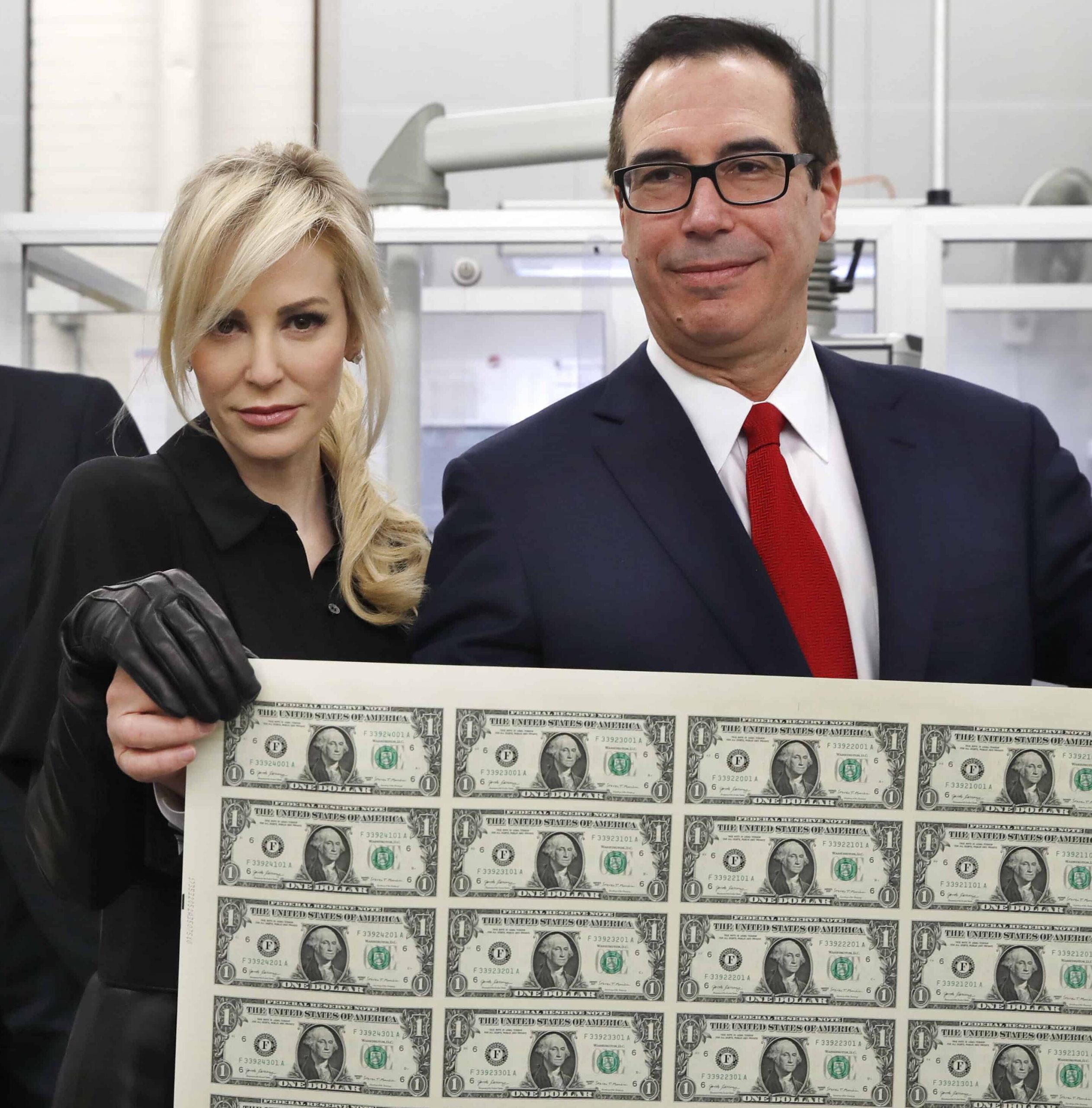 Treasury Secretary Steven Mnuchin, right, and his wife Louise Linton, hold up a sheet of new $1 bills.