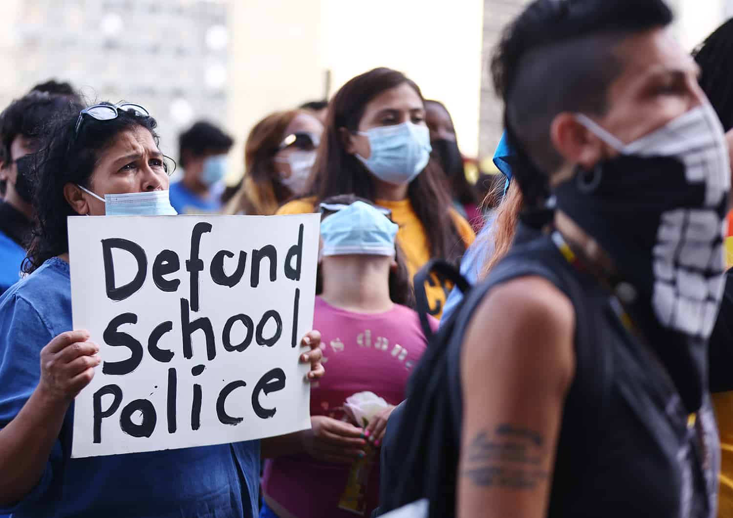 A protester holds up a sign that says 'defund school police' outside the Unified School District headquarters in Los Angeles.