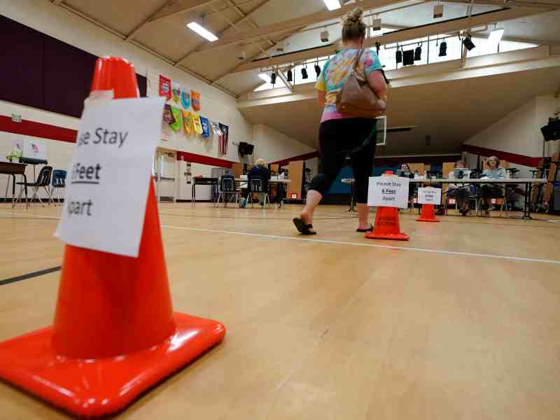 A voter walks up to seated poll workers so she can cast her ballot.
