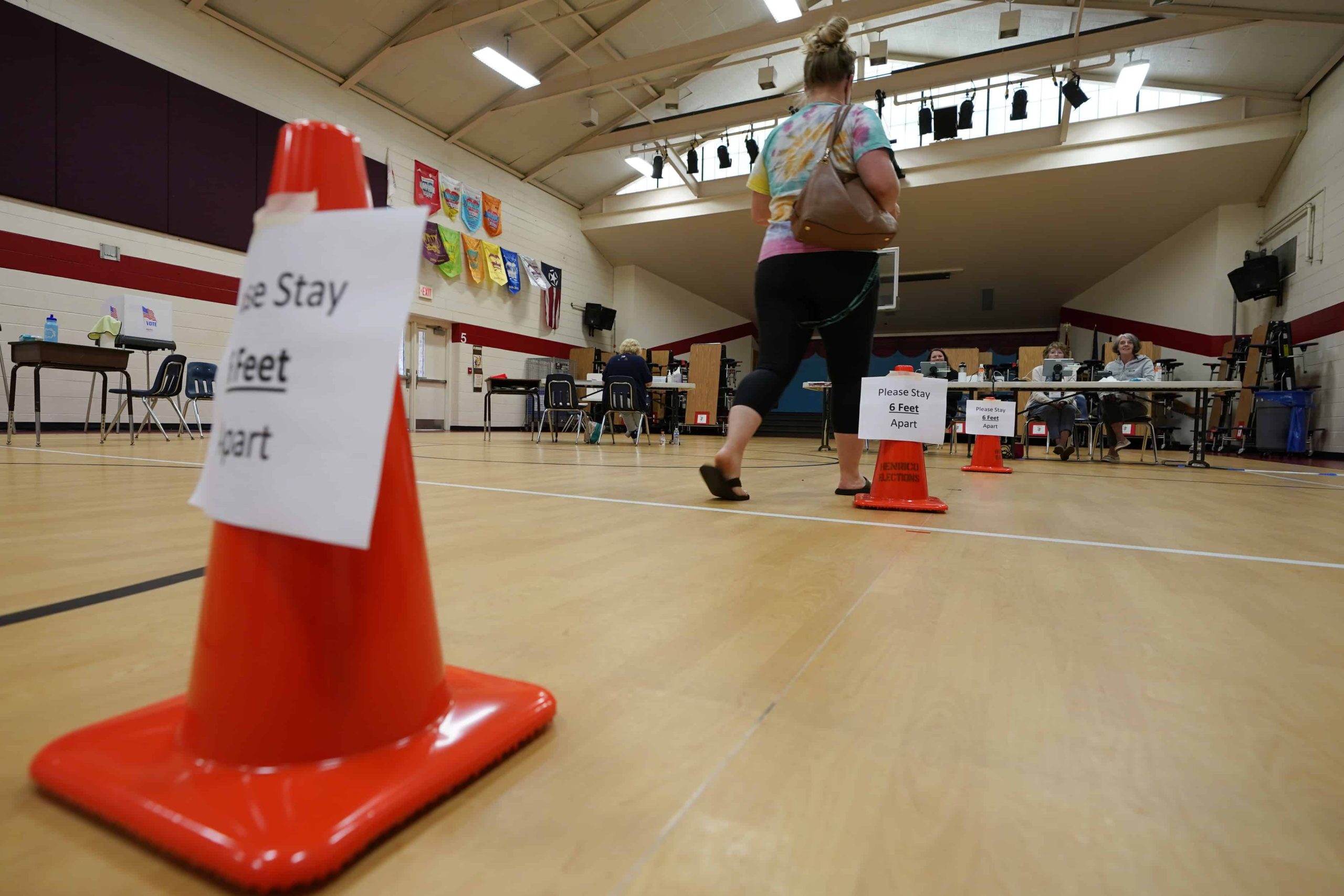 A voter walks up to seated poll workers so she can cast her ballot.