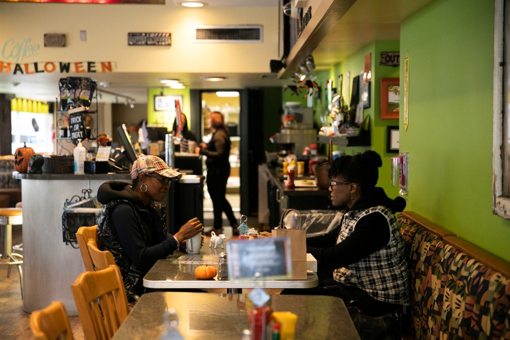 Shonda Young talks with business owner Rosie Daniel of LuLit’s Hair Essence at a cafe in Waterloo.