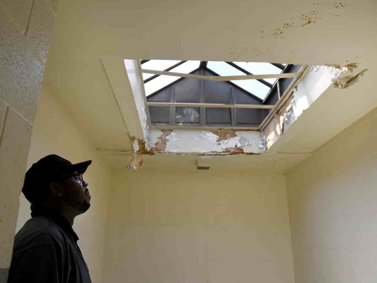 A photo of a D.C. Housing Authority maintenance supervisor looking at water damage to a stairwell skylight in a public-housing complex