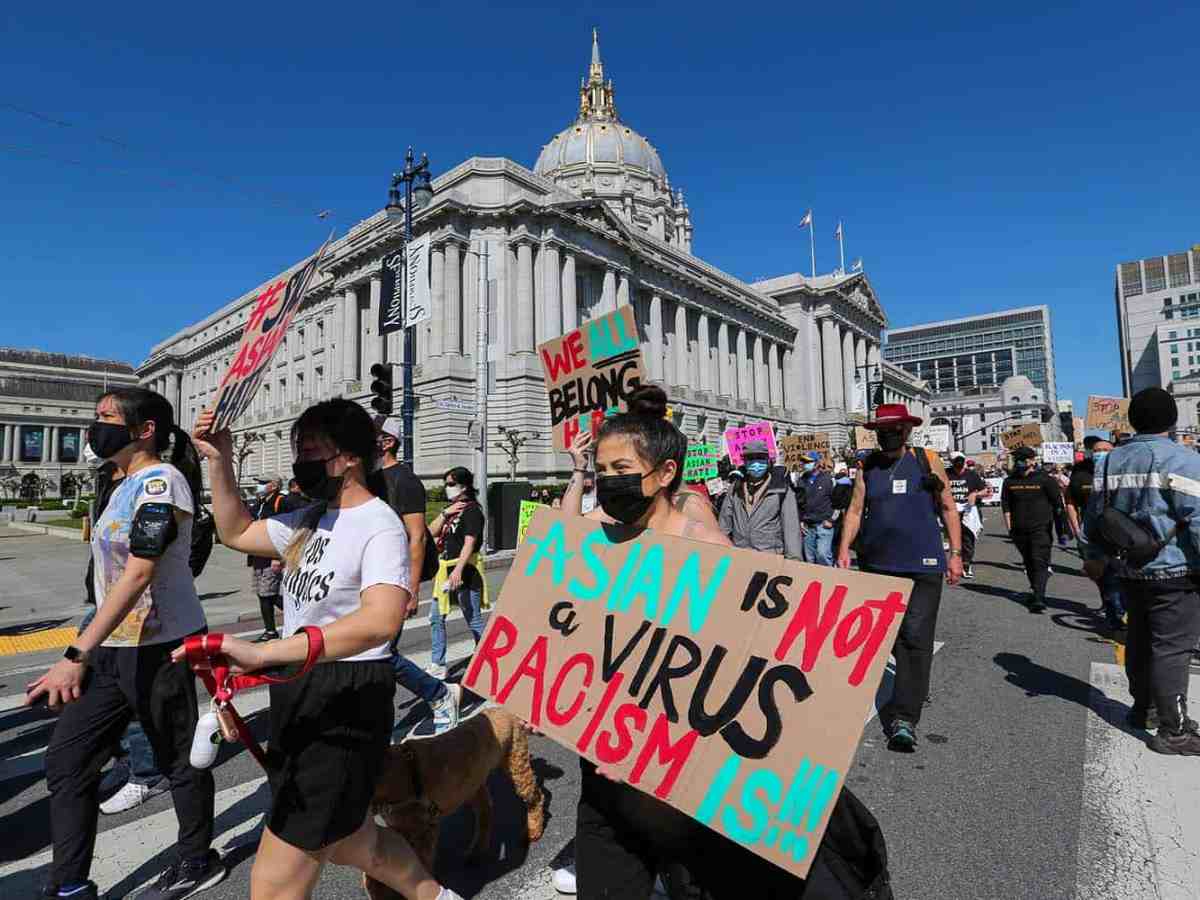 Demonstrators hold up signs that say "Asian is not a virus. Racism is!!!"