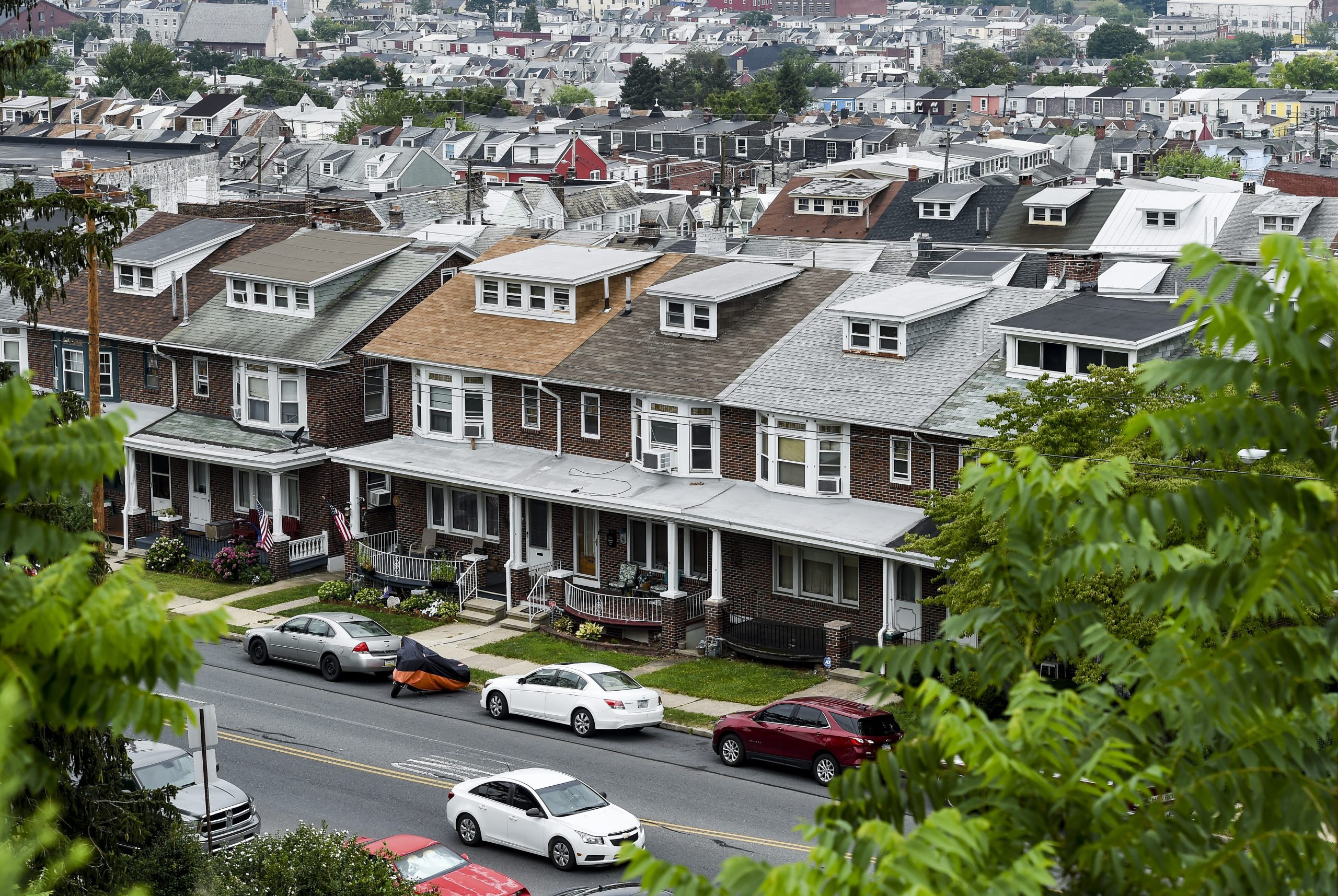 A sky-high view of a block of row homes. You can also see cars parked on the street.