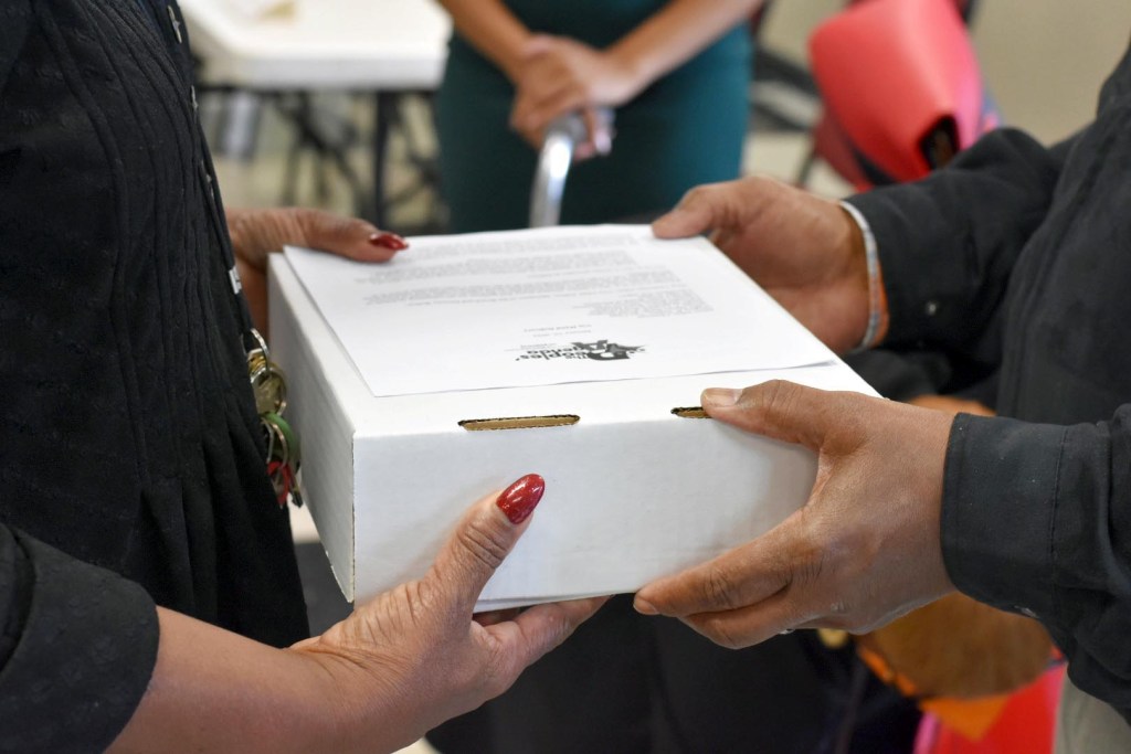 Two people deliver a petition with more than 600 signatures in a box.
