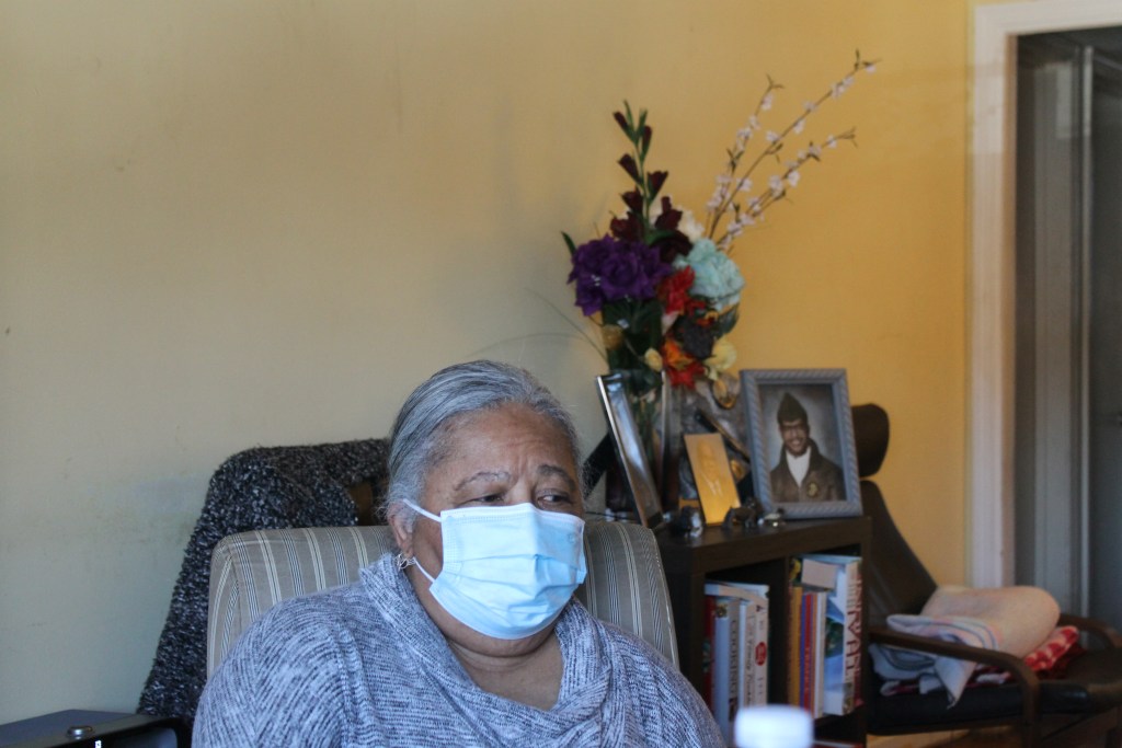 Patricia Robinson sits in front of portraits of her family in her home in Washington, D.C.