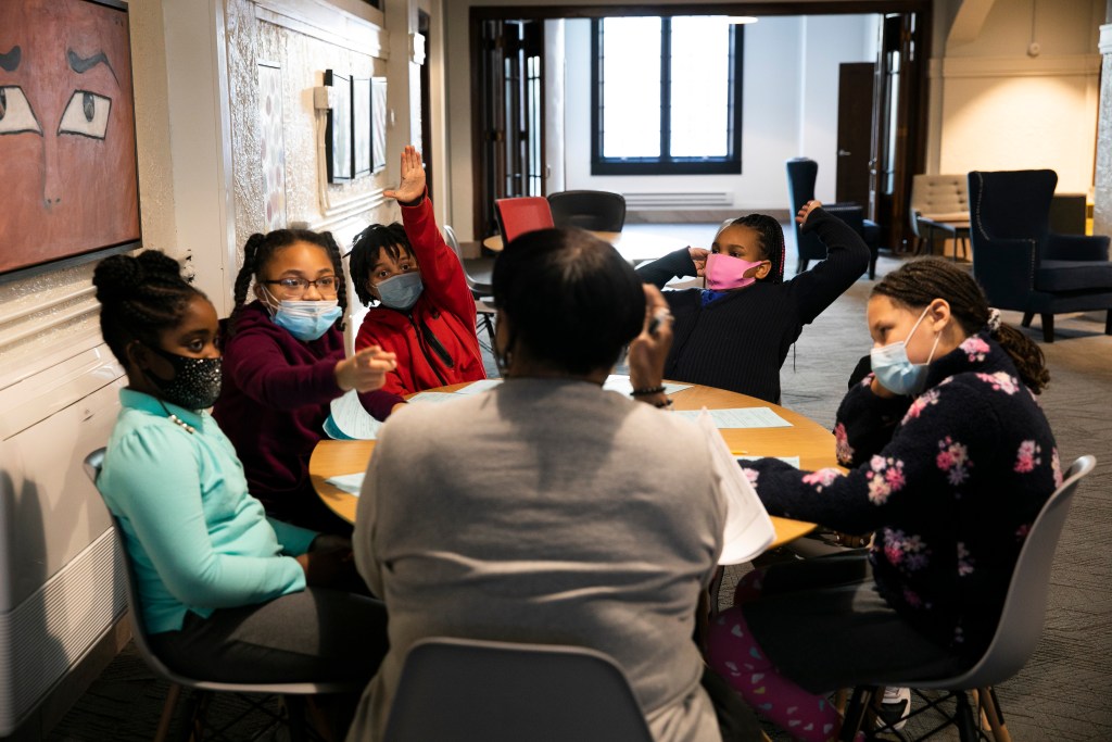 Mary Wilder reads the book “The Youngest Marcher: The Story of Audrey Faye Hendricks, a Young Civil Rights Activist” to fourth- and fifth-grade students at a round table at the 1619 Freedom School in Waterloo.