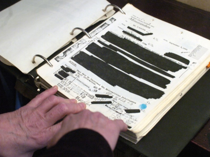 Redacted documents are in a binder.