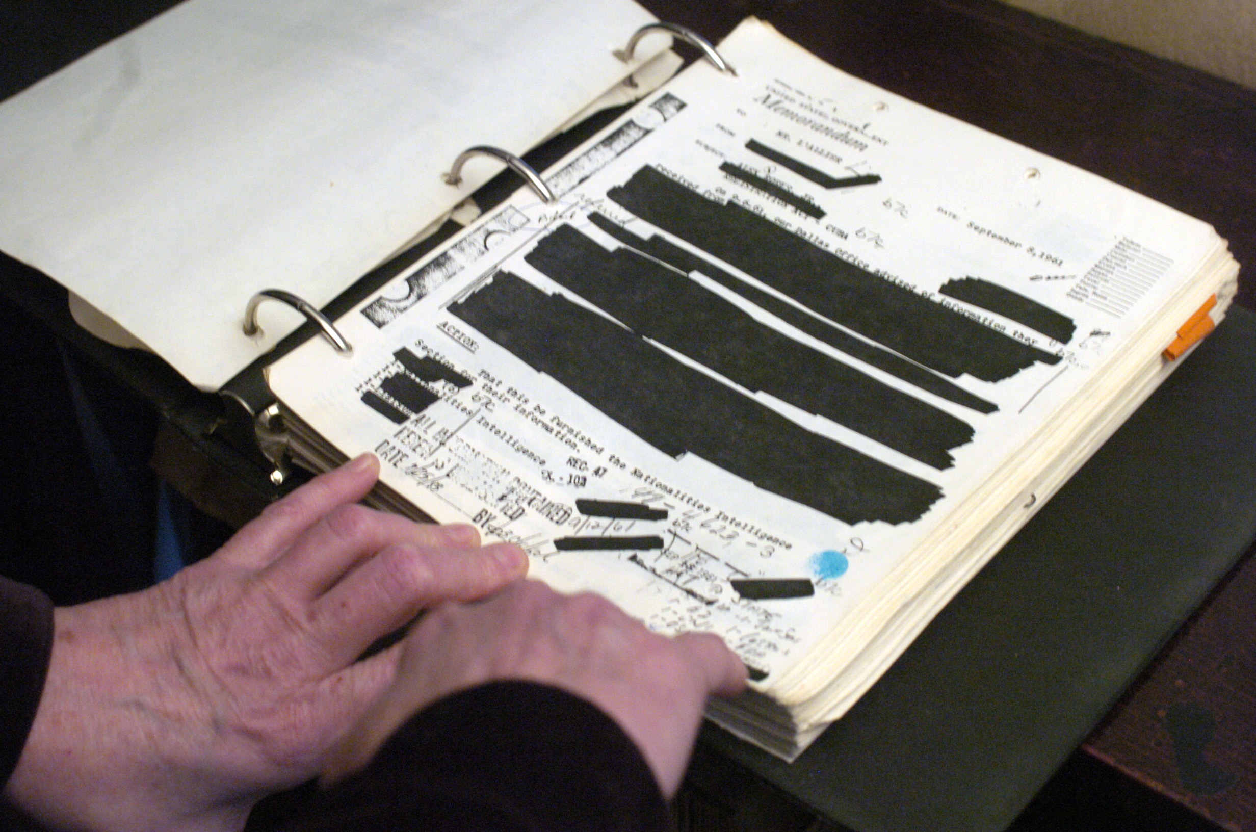 Redacted documents are in a binder.