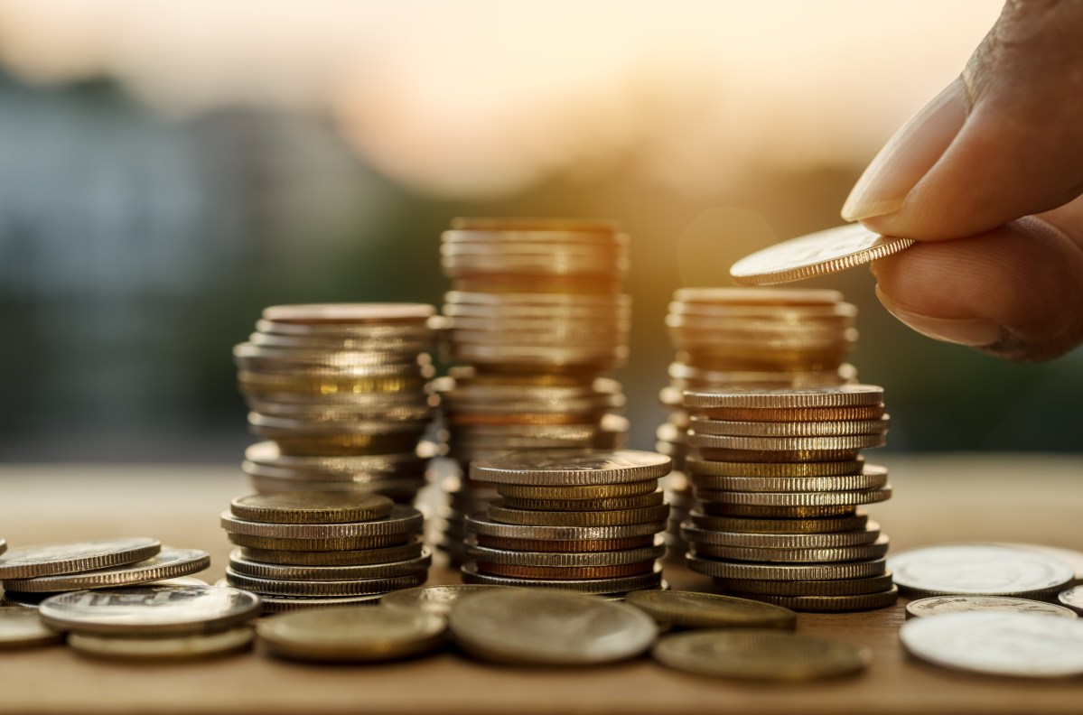 A hand stacks coins on a table.