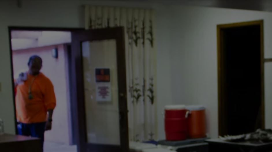 Man wearing orange polo stands in door of donation center.