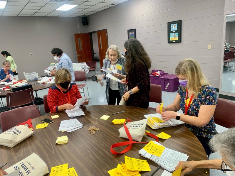 League of Women Voters members sit at a table as they prepare to hand out voter registration forms.