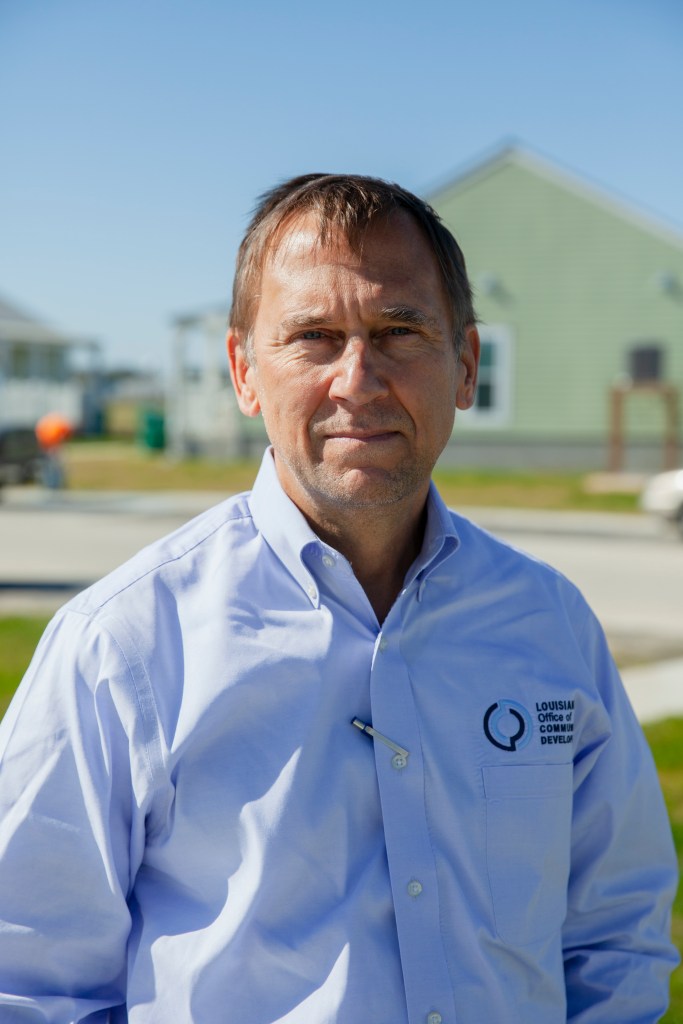 Pat Forbes is seen outside dressed in a blue button-down shirt with a pen tucked between his buttons. 