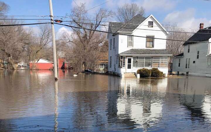 You can see the climate change impact here: A street is flooded. You can see several homes have water as high up as the front porch.
