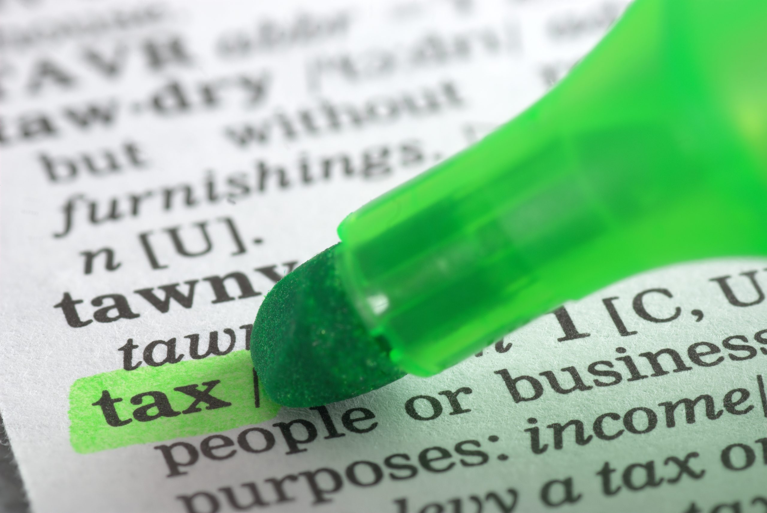 The word tax is highlighted in a dictionary with a green marker.