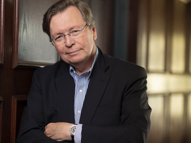 Charles Lewis leans agains the wall with his hands folded.