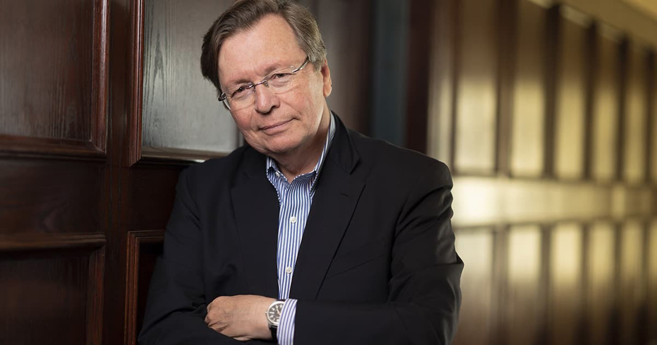 Charles Lewis leans agains the wall with his hands folded.