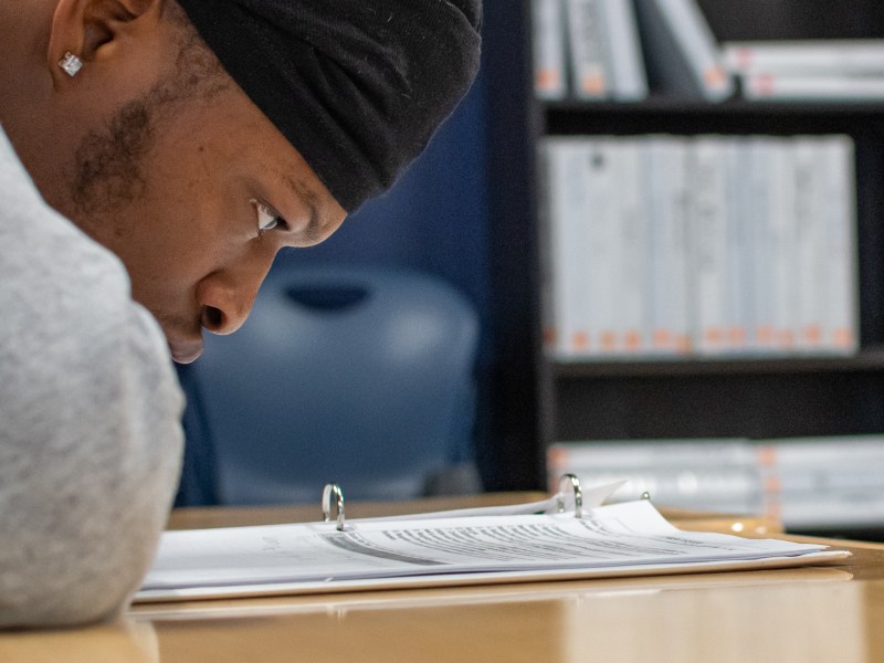 A close up of Tyequan Colkey as he reads text from a binder.