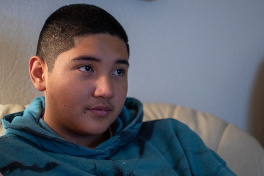 Guadalupe Hernandez, seated, looks at someone off-camera, an earnest expression on his face
