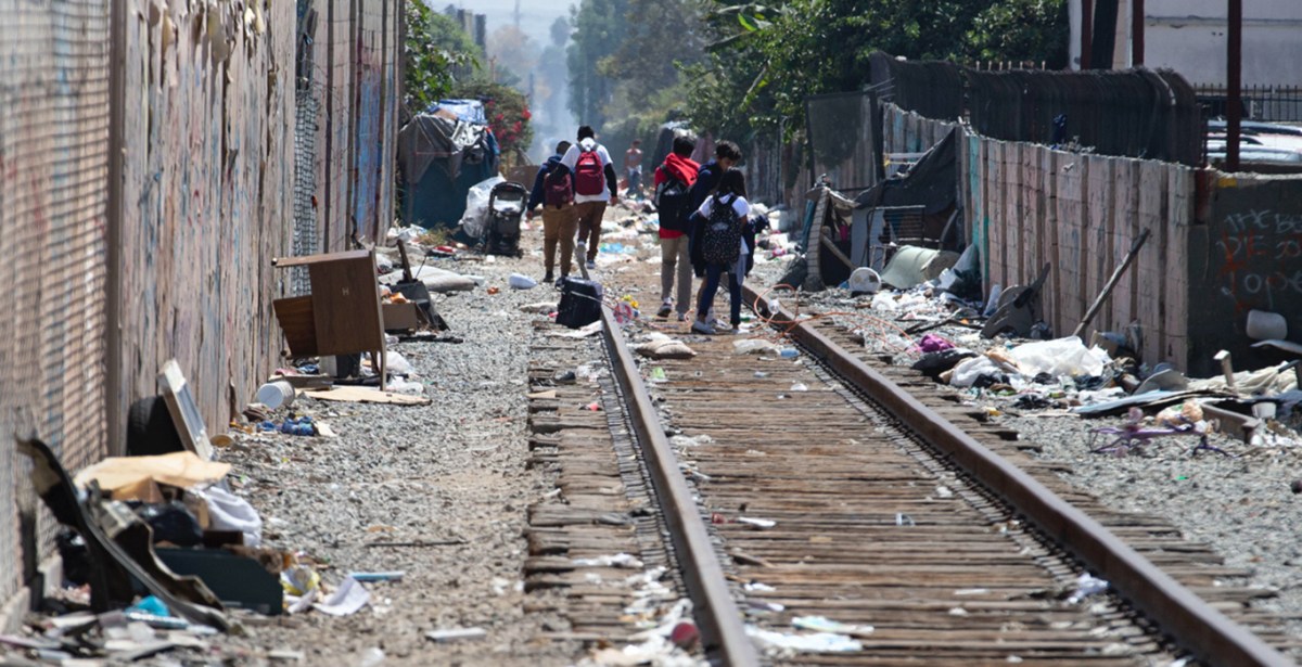 Santa Ana children walk along the train tracks that are littered with debris.