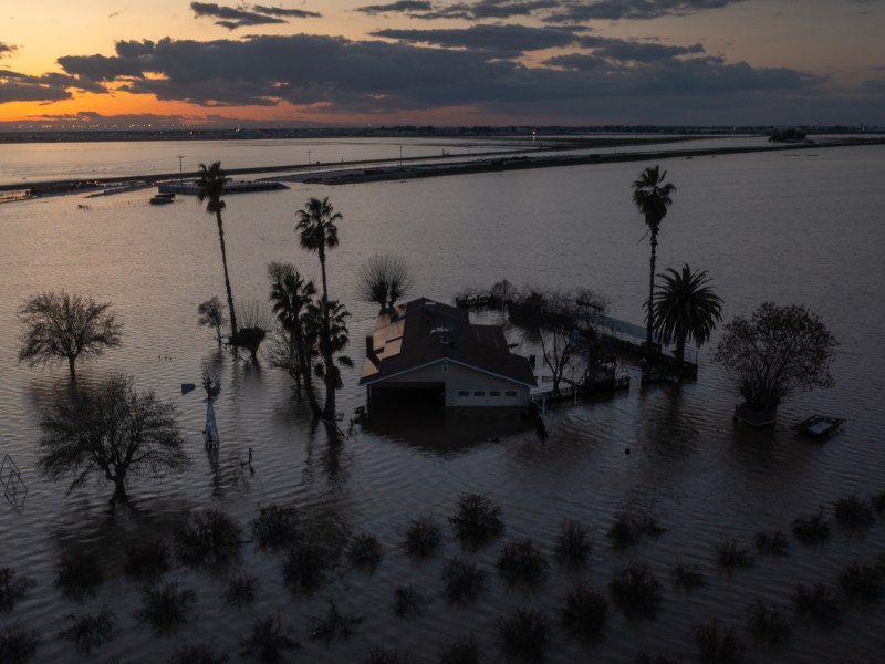 A house sits half submerged in flood water after a storm