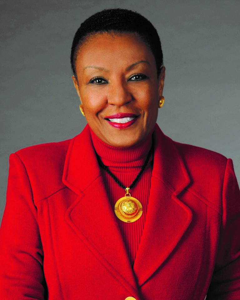 In this headshot, Leah Ward Sears is wearing a red turtleneck and matching red blazer with a necklace that has a gold pendant. She is smiling.