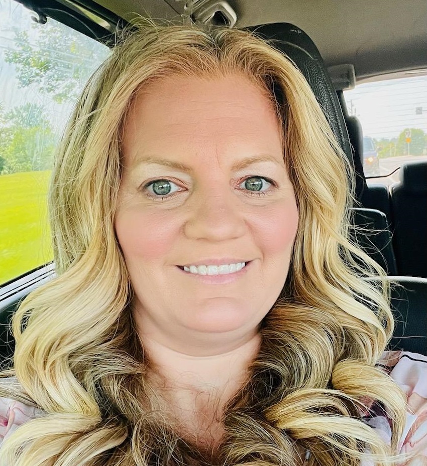 Meghan O’Connor is smiling in this headshot. She is sitting in a vehicle.