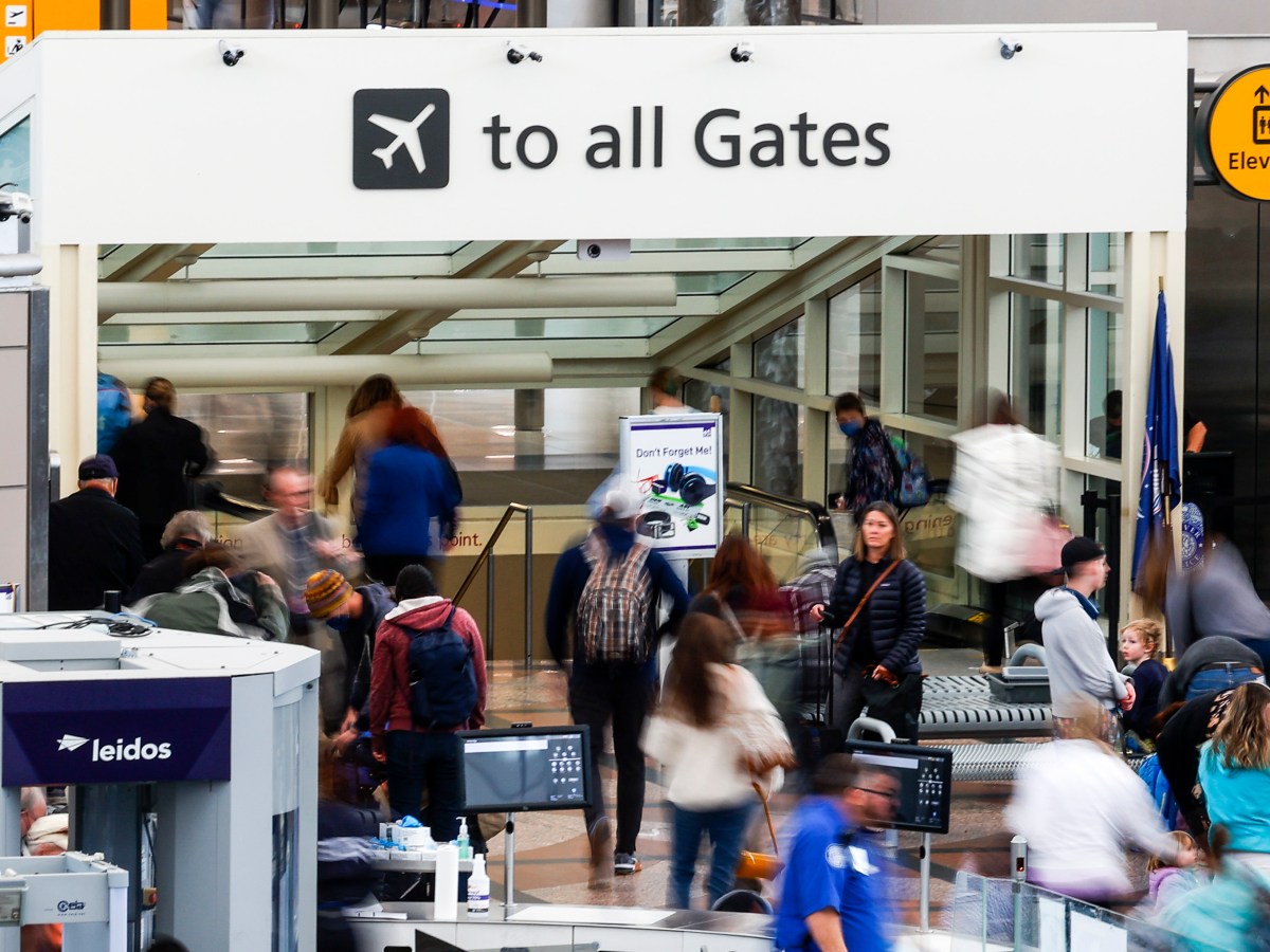 The photo shows people, some blurred in movement, at an airport.