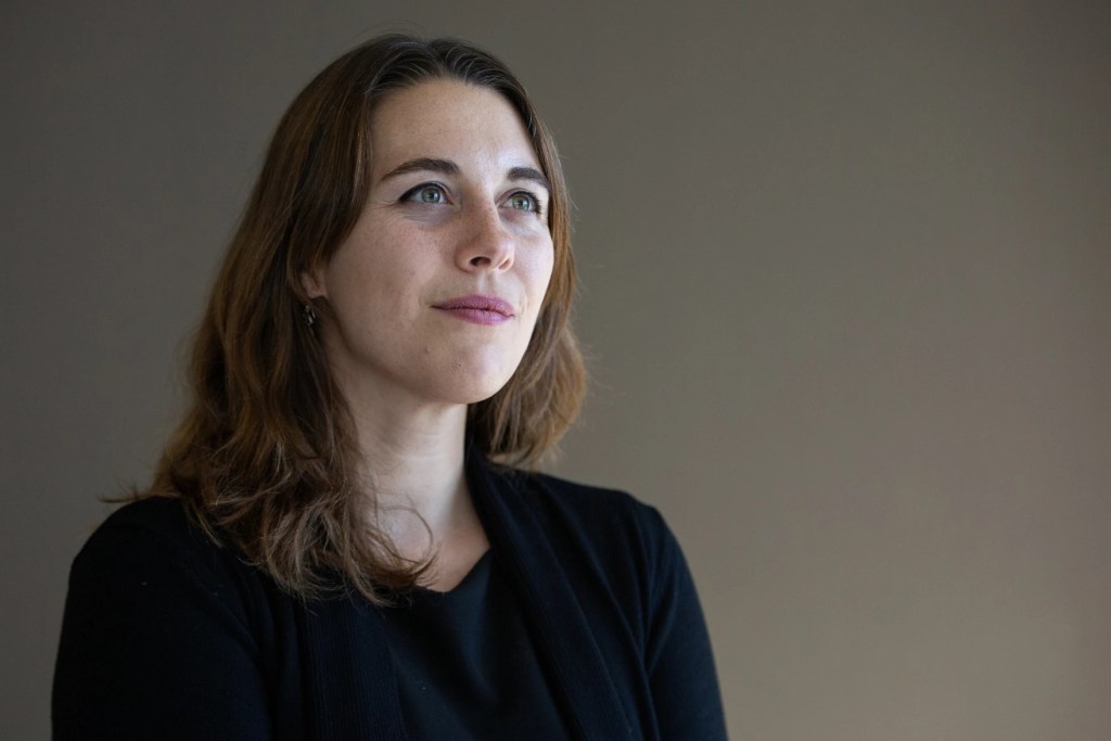 Hopey Fink is looking slightly off-camera with a small smile. She has mid-length brown hair.