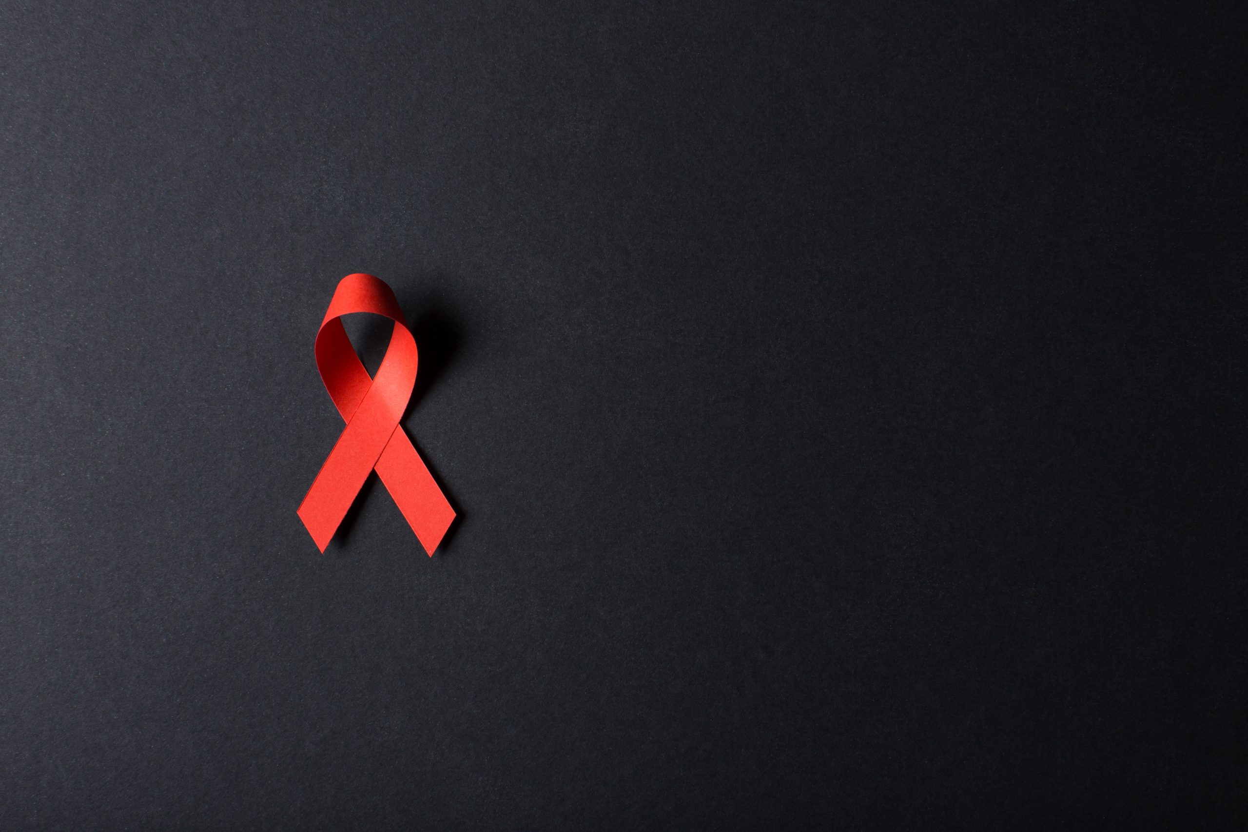 High angle view of a red paper awareness ribbon on a black background.