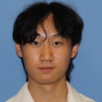 Nathan Yuan is looking into the camera with a small smile, against a blue background.