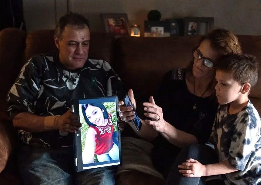 Sitting on a brown leather couch, Freddy Corona and Shawna Normali look at photos of their daughter, Lena Corona, with their son Josh Corona. Lena was in psychosis in July when she was arrested and taken to the Seminole County jail where she died by suicide.