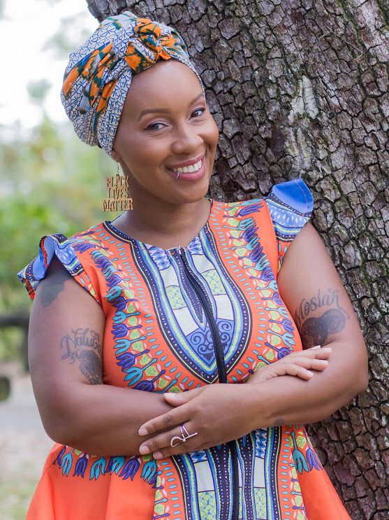 Jamarah Amani poses by at tree.