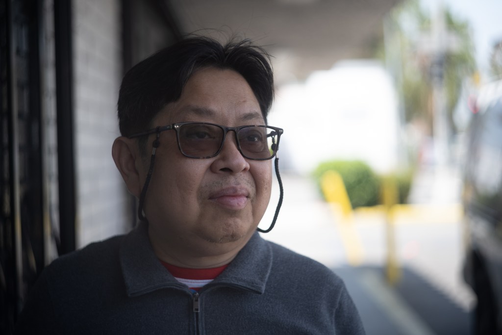 Gabriel Roque is wearing glasses and looking slightly off camera with a serious expression