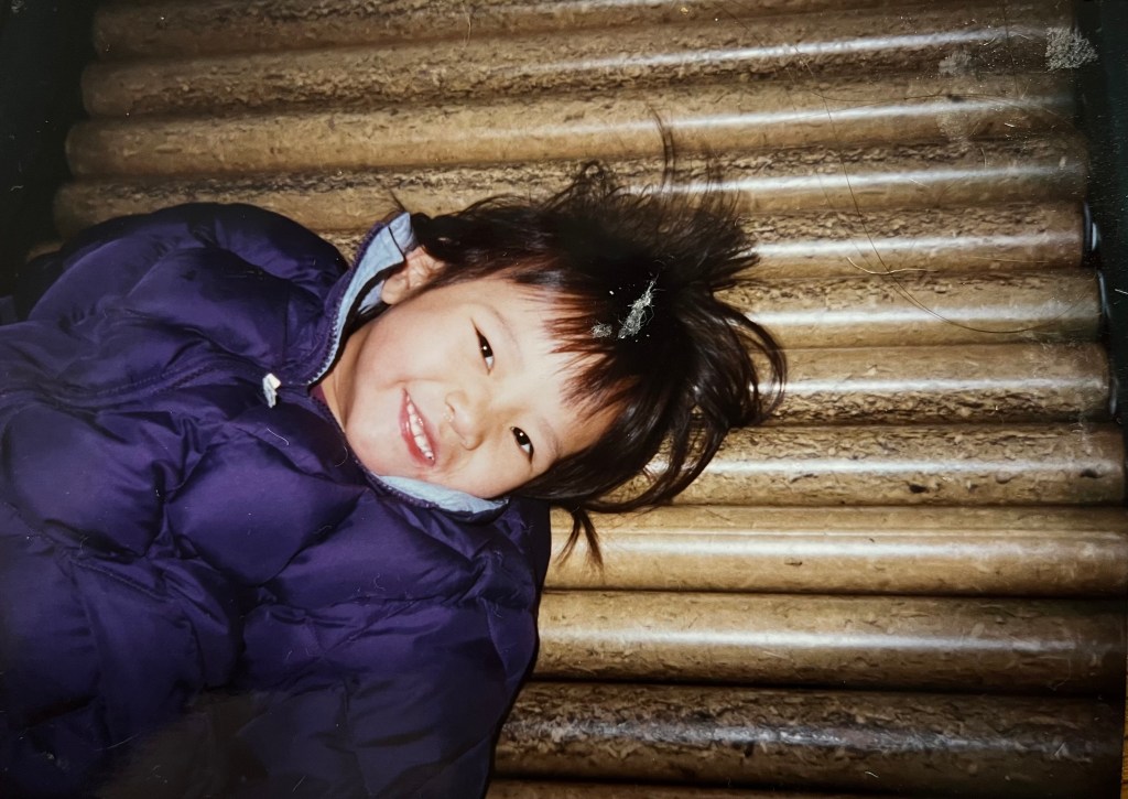 Lian is wearing a puffy winter coat and smiling