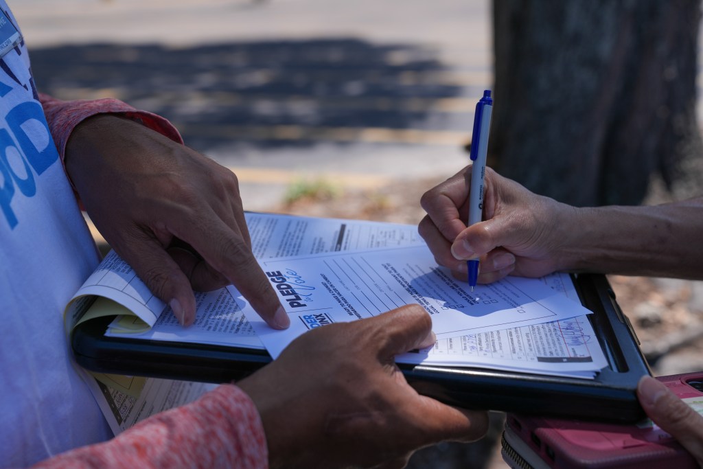 In this close-up photo, Humberto Orjuela is holding a form steady while someone checks a box.