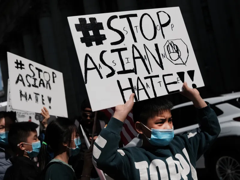 Several children, two holding "Stop Asian Hate" signs, are visible in the close-up shot of the protest.